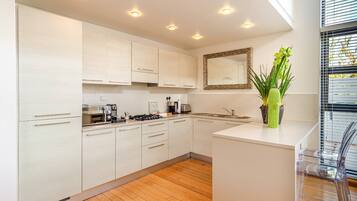 A modern kitchen with white cabinets, a central island, and a large window with blinds.