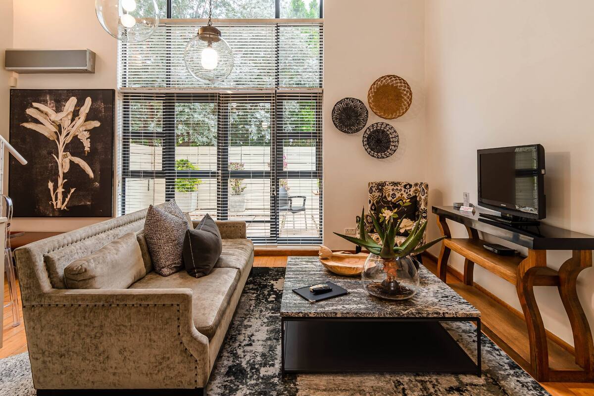 Ein Wohnzimmer mit einer Couch, einem Couchtisch, einer TV-Kommode und Dekorationselementen.