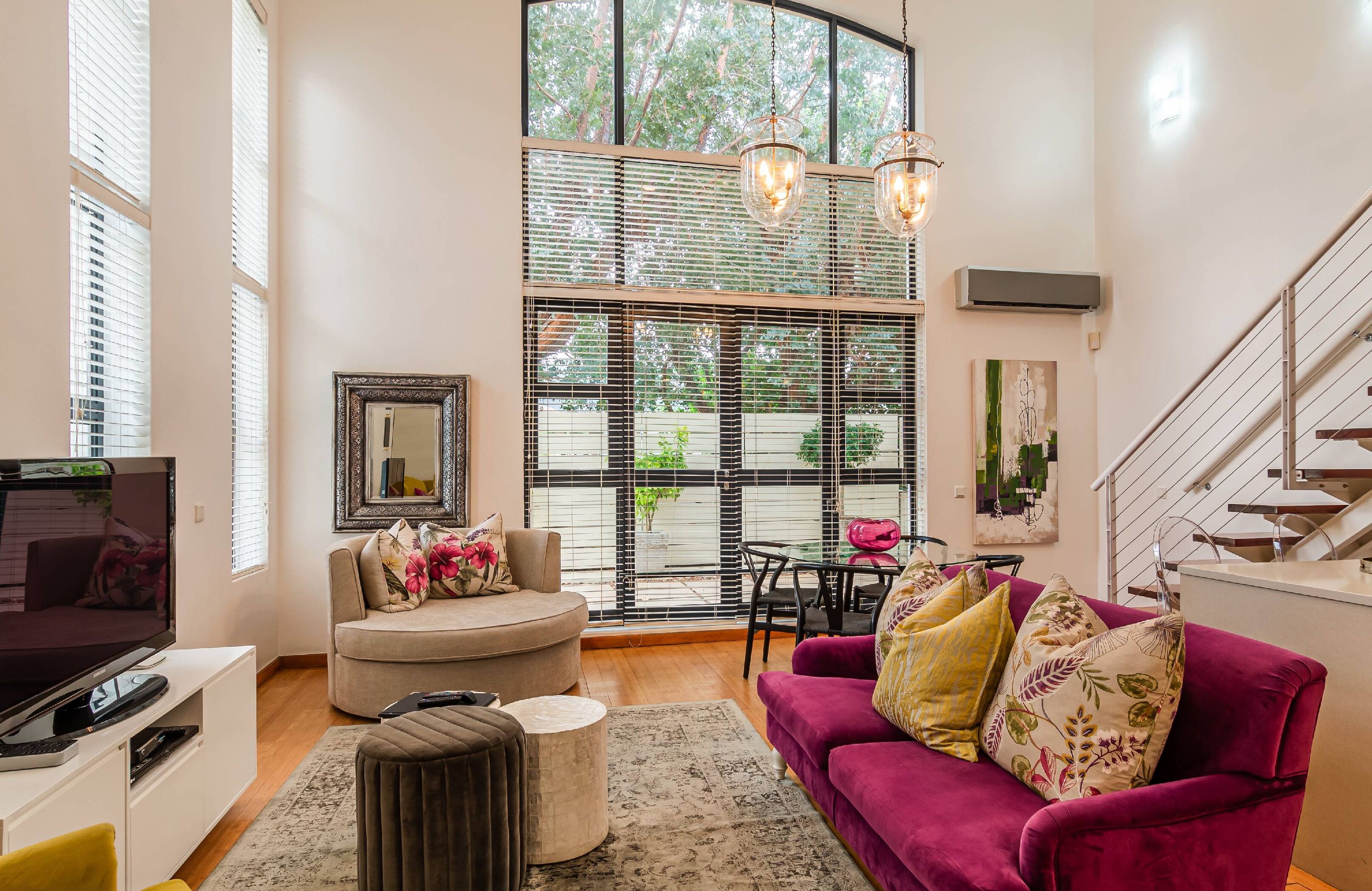 A spacious living room with a large window, a sofa, a coffee table, and a TV.