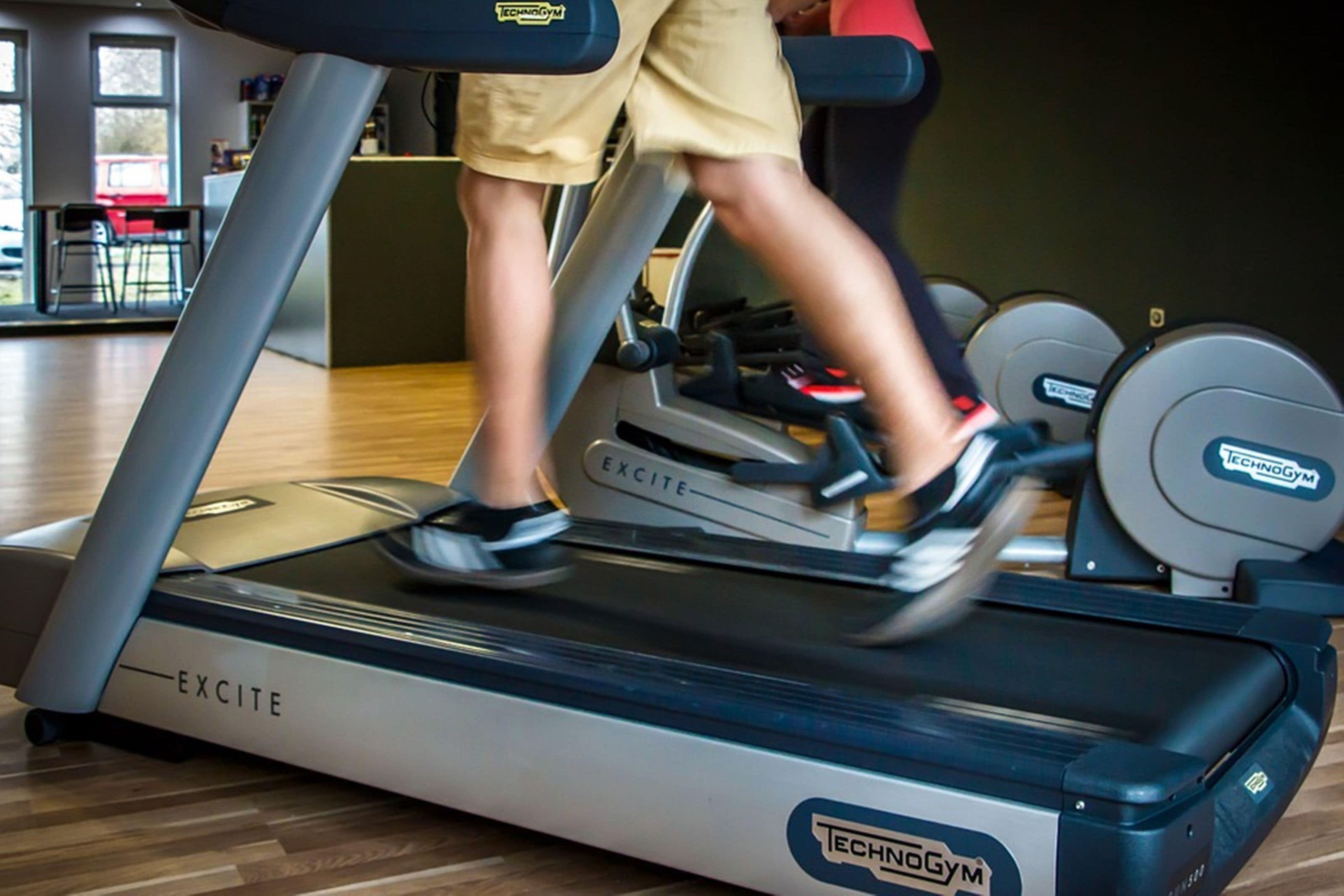 A treadmill with the brand name 'EXCITE' and 'TECHNOGYM' visible, indicating a gym setting.