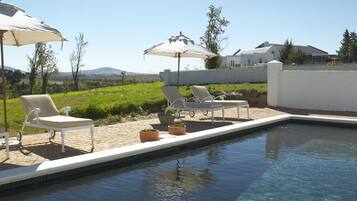 Una piscina al aire libre, sombrillas, tumbonas