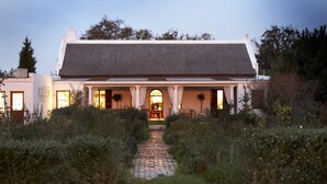 A house with a paved pathway leading to a front door, surrounded by greenery. - Hawksmoor House (Cape Town)