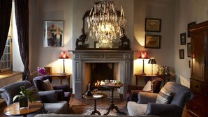 A cozy living room with a fireplace, elegant chandelier, and comfortable seating. - Hawksmoor House (Cape Town)