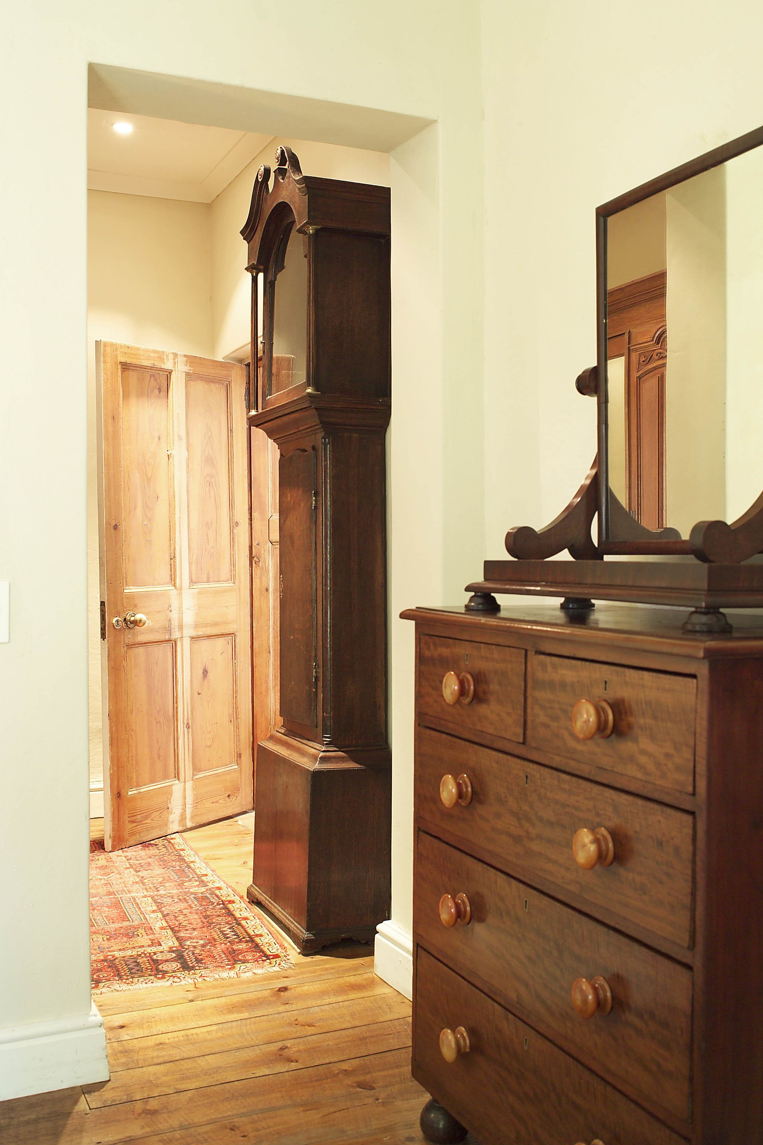 A room with a wooden dresser, a mirror, and a tall wooden cabinet.