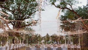 An outdoor wedding venue with tables set up under a canopy of string lights and surrounded by trees. - Hawksmoor House (Cape Town)