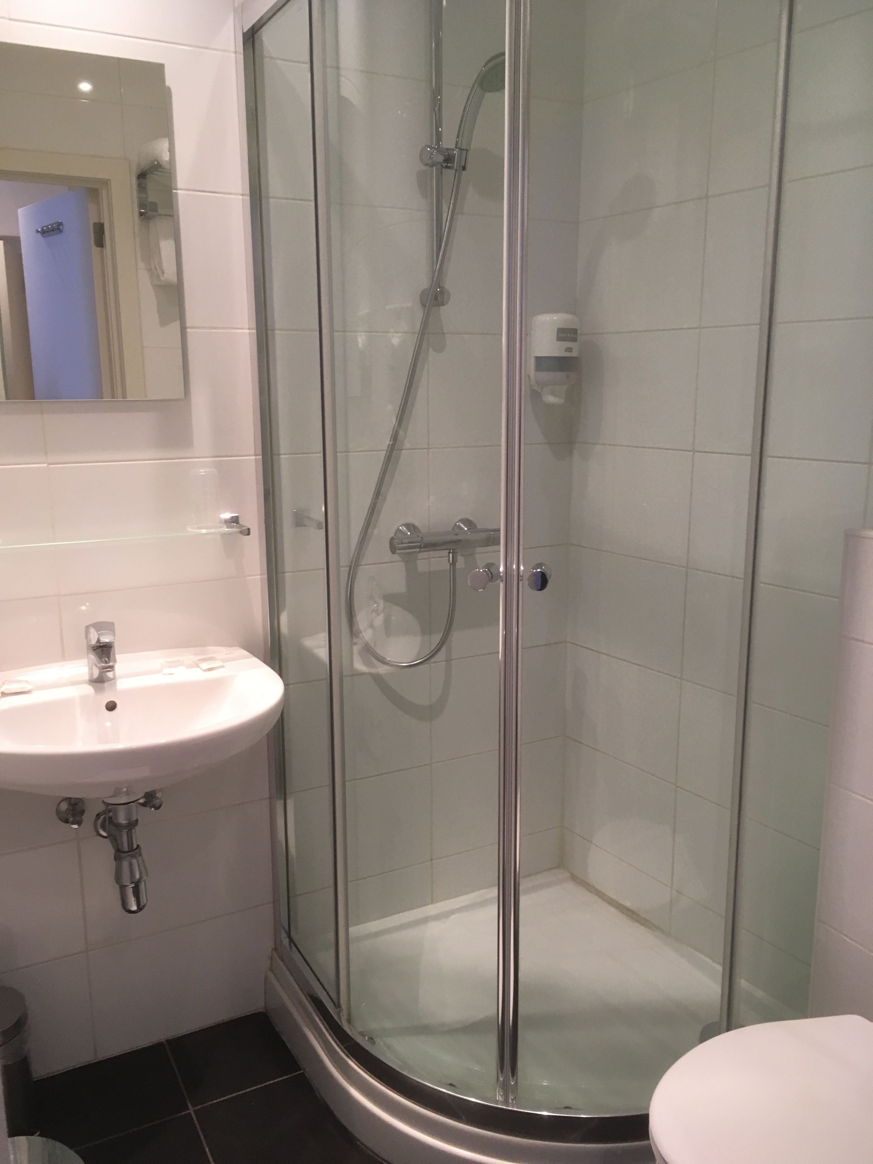 Une salle de bain avec une douche à parois de verre, un lavabo et des toilettes.