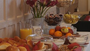 Un buffet con diversi cibi, tra cui frutta, dolci e salumi, disposti su un tavolo.