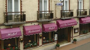 Un hotel con diversi balconi, un cartello che indica 'HOTEL DU COMMERCE' e vetrine con scritto 'Hotel' e 'Ristorante'.