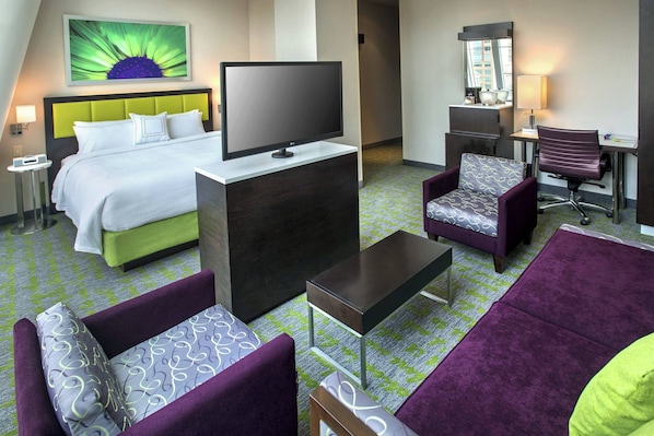 A hotel room with a bed, a TV, a desk with a chair, and two sofas. - SpringHill Suites by Marriott New York Midtown Manhattan (New York)