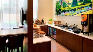 Un espace dédié au petit-déjeuner, avec un comptoir, des sièges et un tableau accroché au mur.