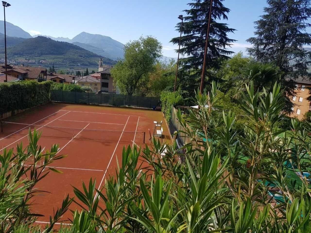 Ein Tennisplatz im Freien, umgeben von üppiger Vegetation und einer Bergkulisse.