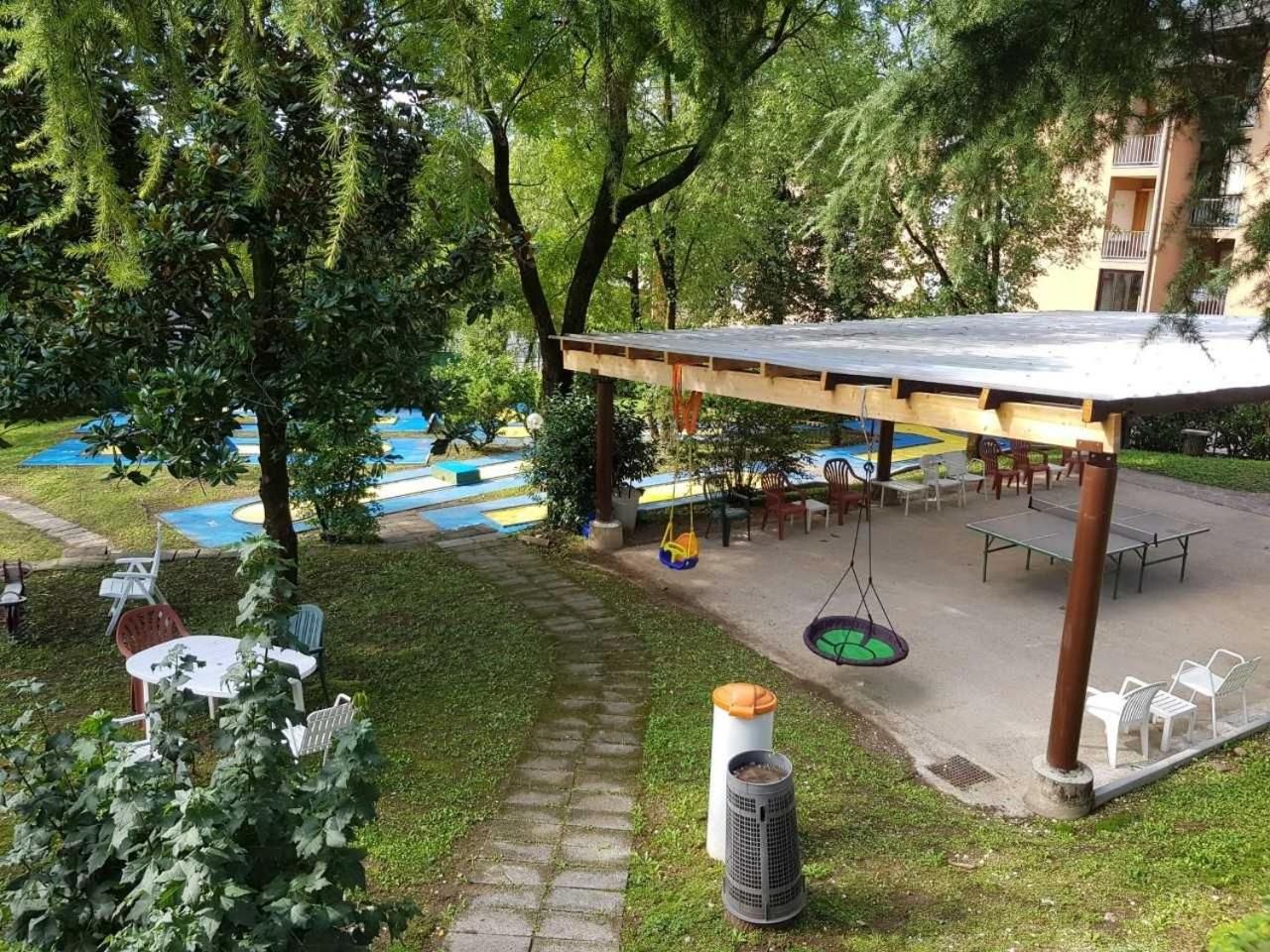 Un espace extérieur aménagé en terrasse, avec des tables et des chaises, une balançoire et un coin salon abrité.