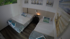 A hotel room with two beds, a nightstand, and artwork on the walls. - Posada Turística Colors Of The Sea (San Andrés)