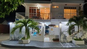 A two-story building with a balcony on the upper floor, a sign indicating bicycle and motorcycle parking, and potted plants in the entrance area. - Posada Turística Colors Of The Sea (San Andrés)