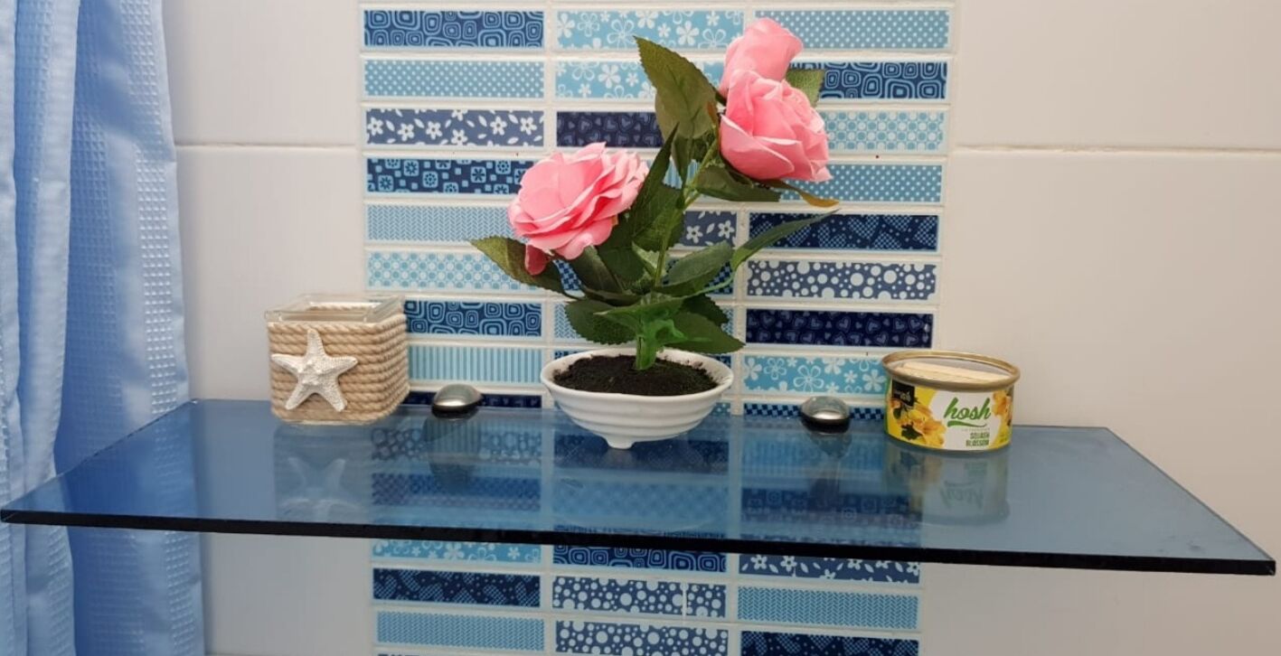 A glass table with a potted plant, a starfish ornament, a small bowl, and a can of honey.