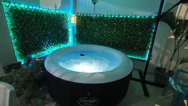 A hot tub with a label, surrounded by green foliage and a blue-lit wall. - Posada Turística Colors Of The Sea (San Andrés)