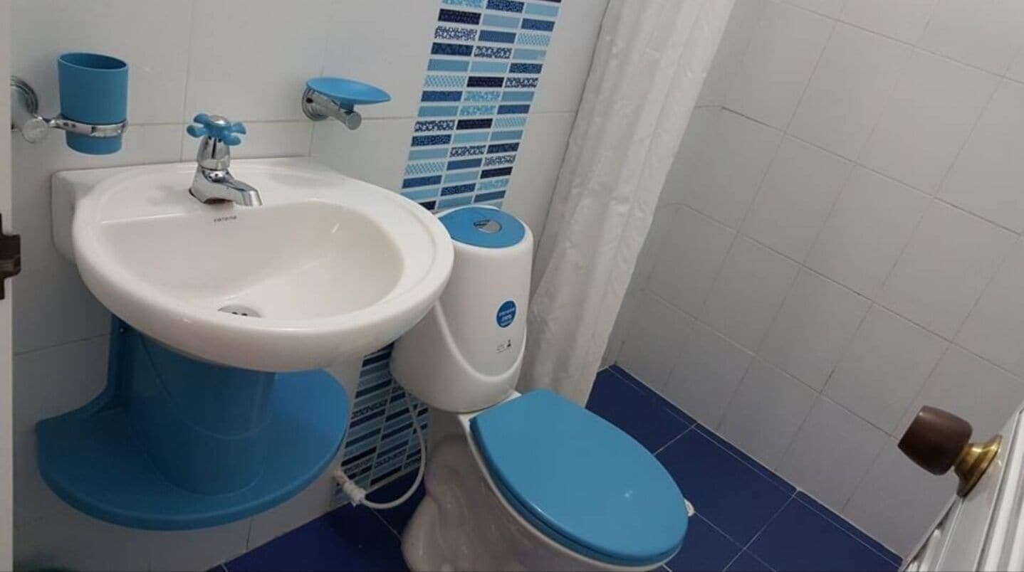 A bathroom with a sink, toilet, and blue-tiled floor.