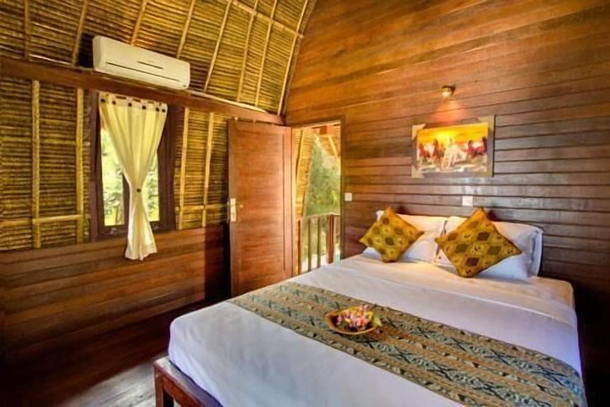 A wooden room with a bed, a window with curtains, and an air conditioning unit.