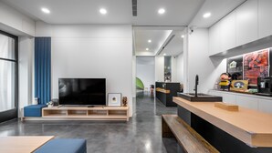 Uma sala de estar moderna com televisão de tela plana, banco de madeira e balcão de recepção.