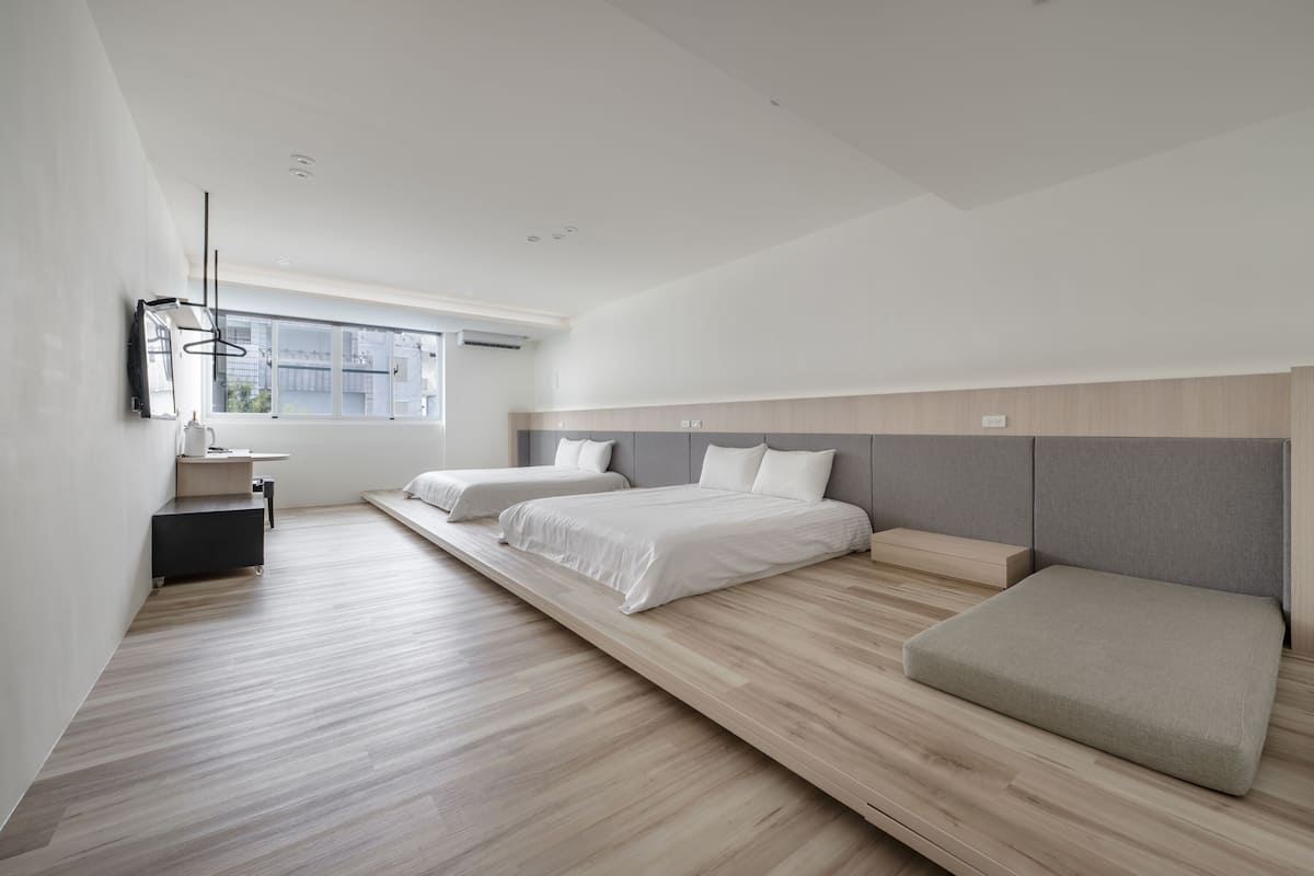 Ein modernes Schlafzimmer mit zwei Betten, einem kleinen Schreibtisch und einem Fenster.
