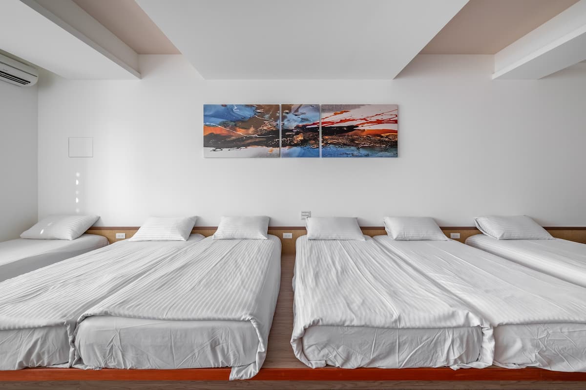 Ein Hotelzimmer mit zwei Einzelbetten, einem großen abstrakten Gemälde an der Wand und einem Holz-Kopfteil.