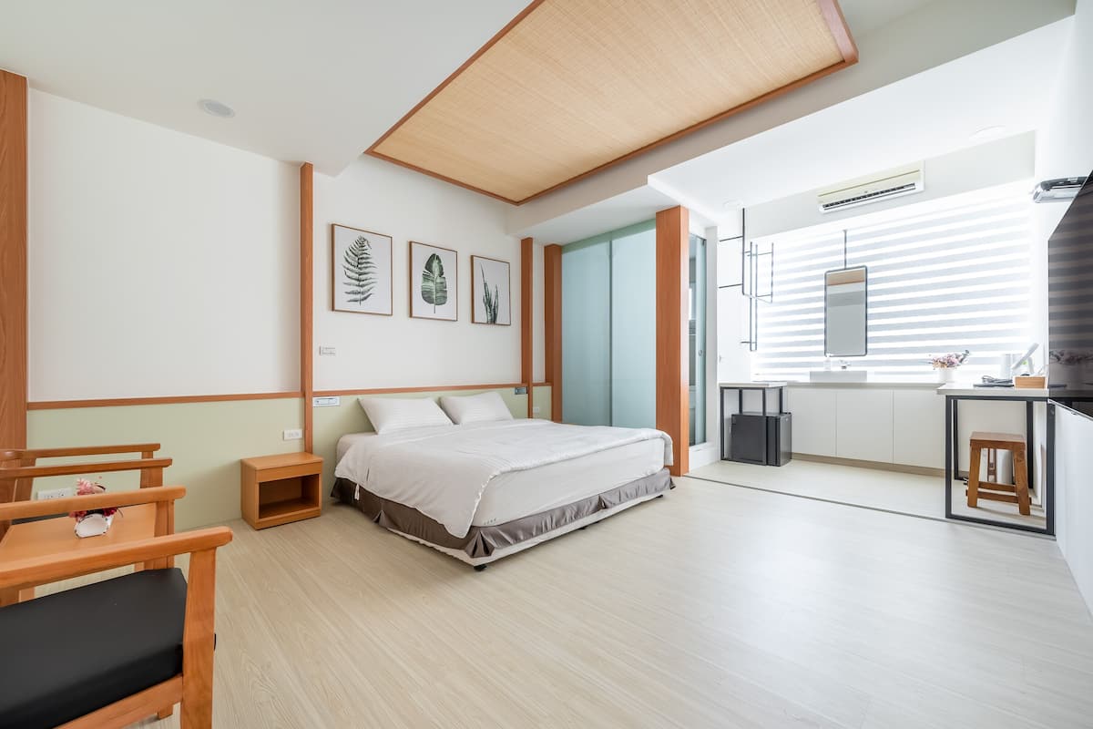 Ein modernes Hotelzimmer mit einem Bett, Nachttischen, einem Schreibtisch und einer Küchenzeile.