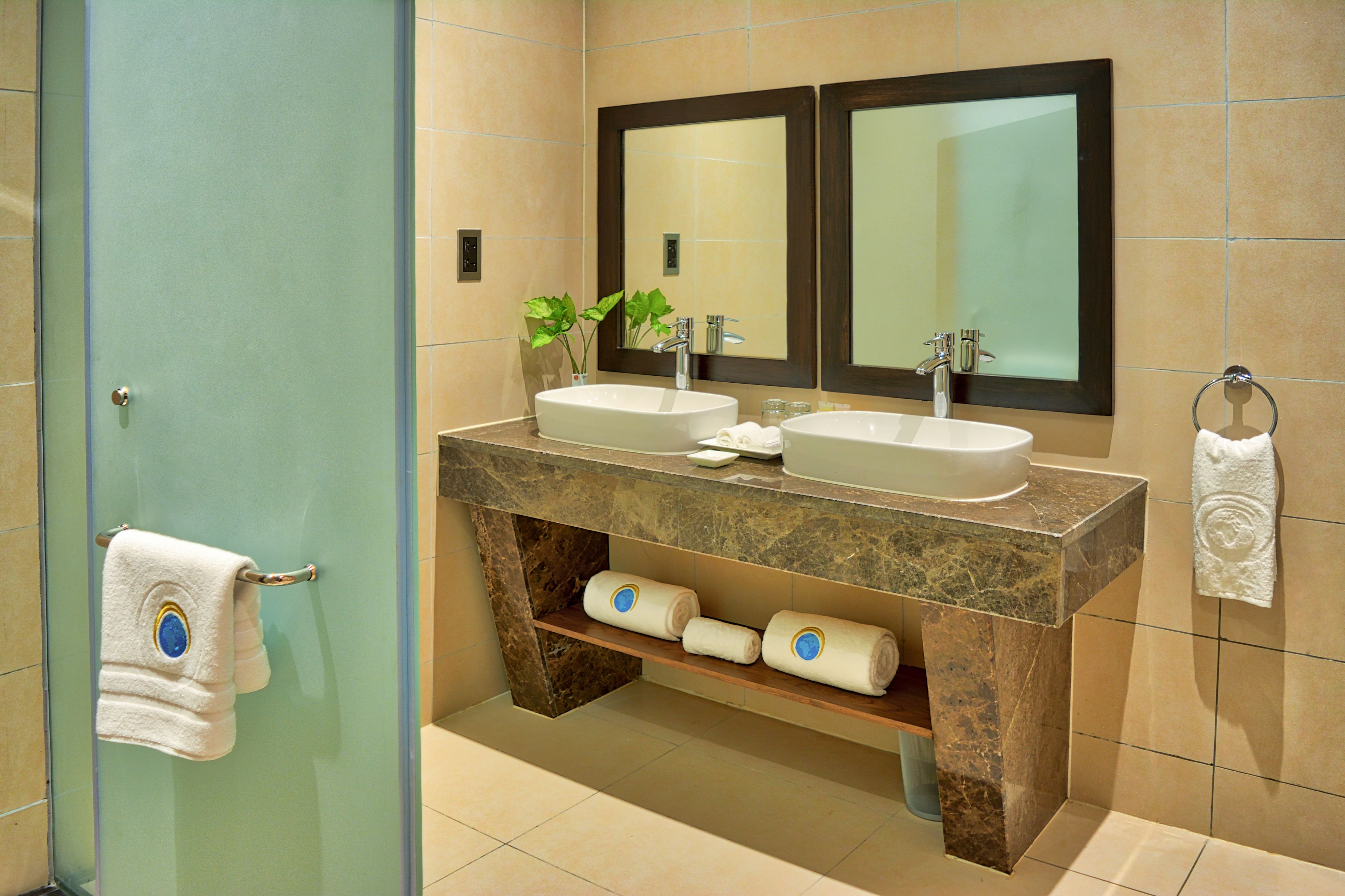 Une salle de bain avec deux lavabos, un miroir et un porte-serviettes.