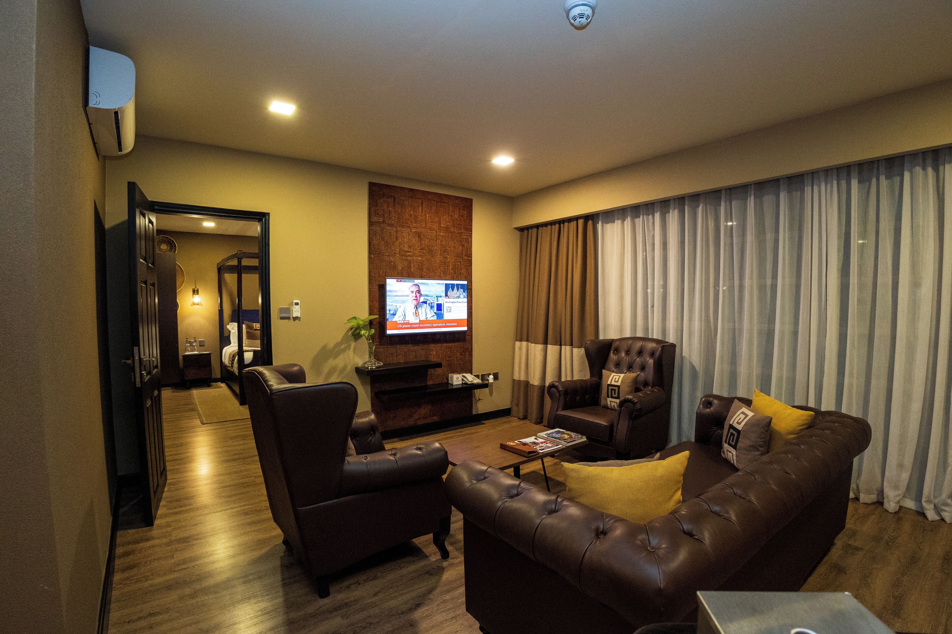 Una sala de estar moderna con sofás de cuero, un televisor de pantalla plana y un mueble de entretenimiento de madera.