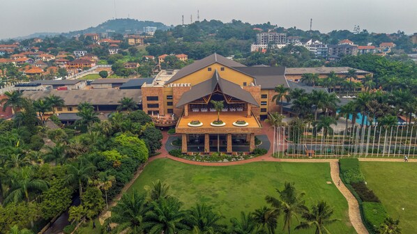 Um hotel grande com um pátio central, rodeado por vegetação exuberante e palmeiras.