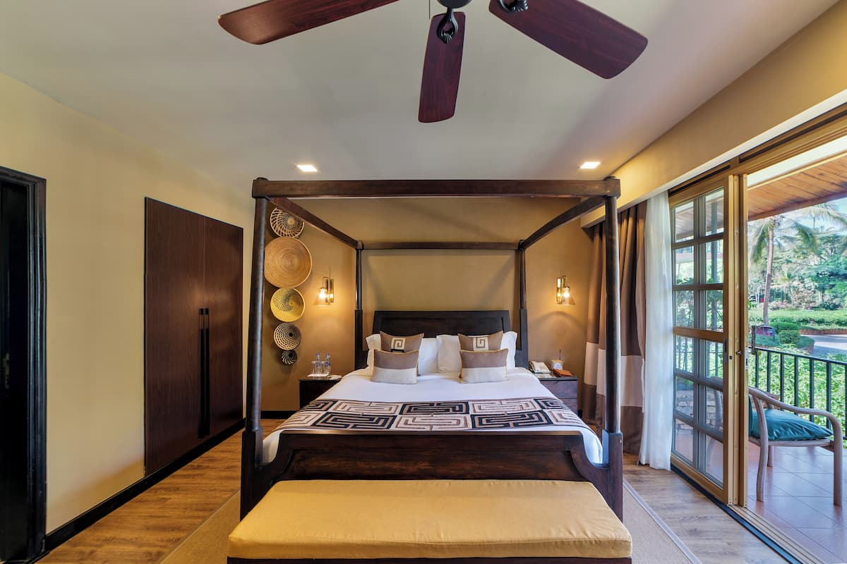 A four-poster bed with a headboard, bedside tables, and a view of the outdoors.