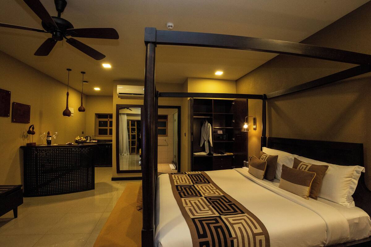 A hotel room with a bed, a ceiling fan, a bathroom, and a desk.