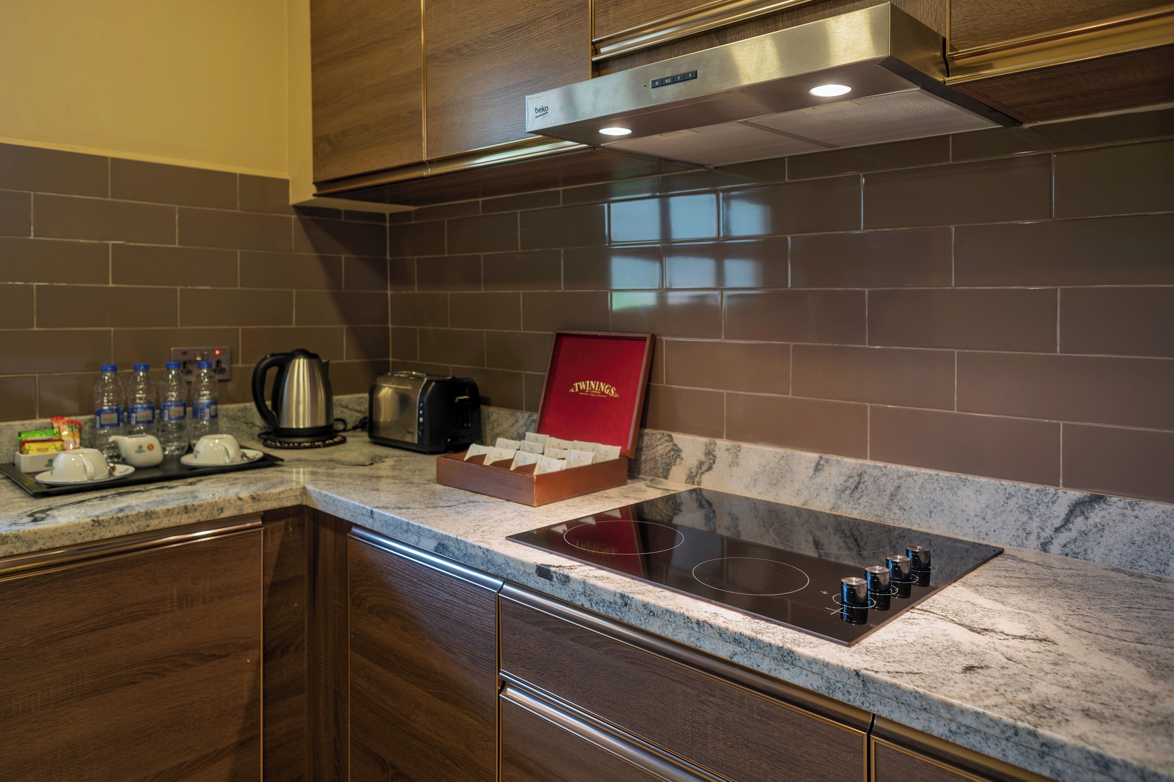 Una cocina moderna con estufa integrada, armarios de madera oscura y salpicadero de azulejos.