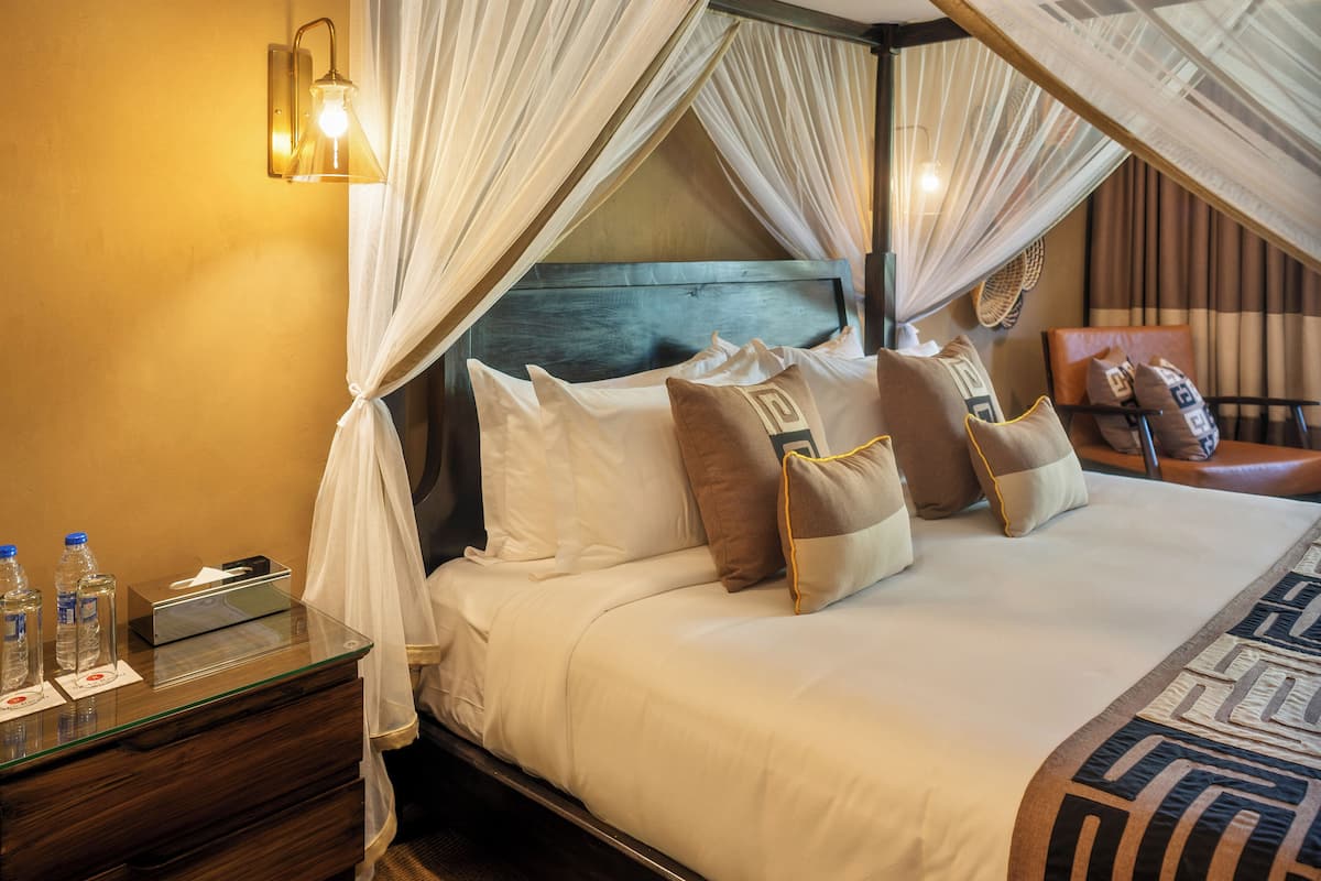 A hotel room with a bed, a nightstand, a lamp, and a chair.