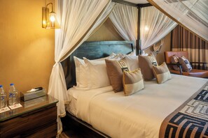 Quarto de hotel com uma cama, mesa de cabeceira, abajur e uma cadeira.