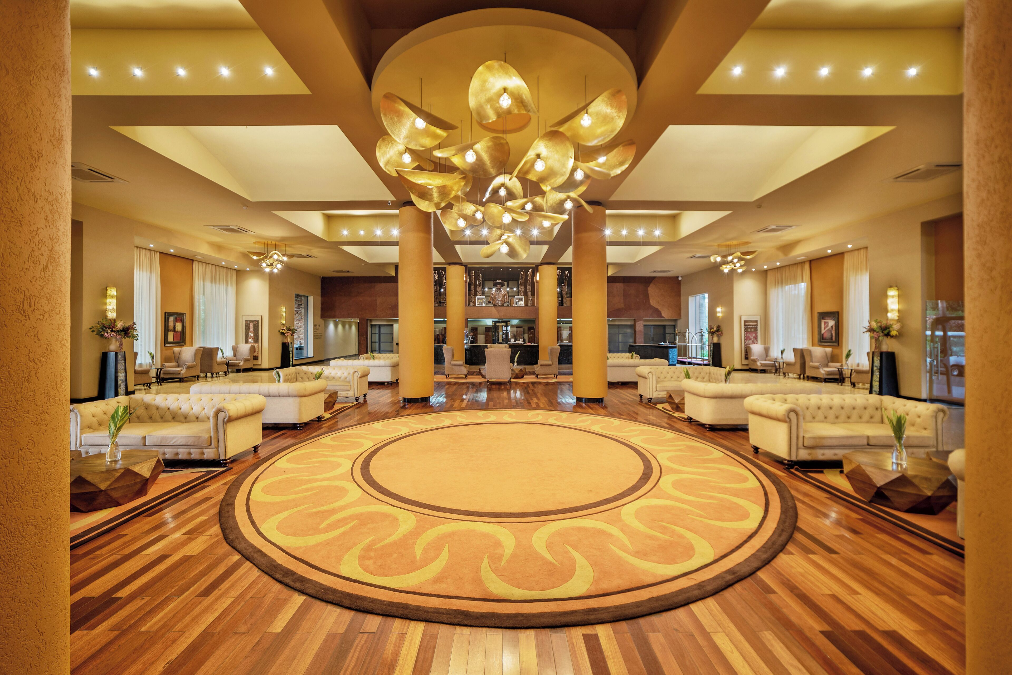 A spacious lobby with a central circular carpet, multiple sofas, and a distinctive ceiling chandelier.