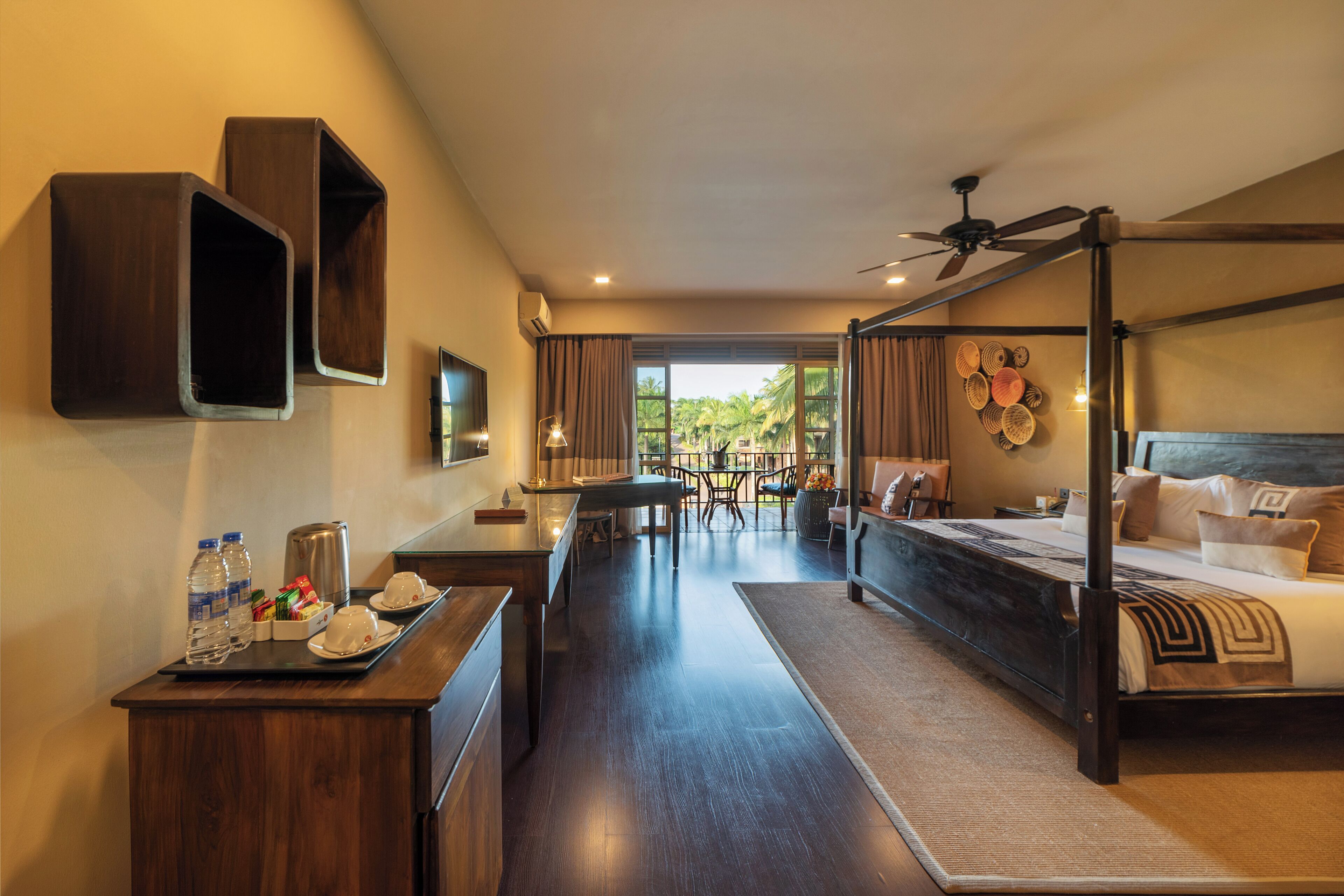 Habitación de hotel con cama con dosel, zona de comedor con mesa y sillas, y vistas al exterior.
