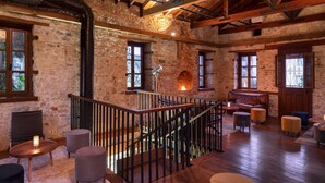 Un interno rustico in pietra con camino, travi in legno e una scala.