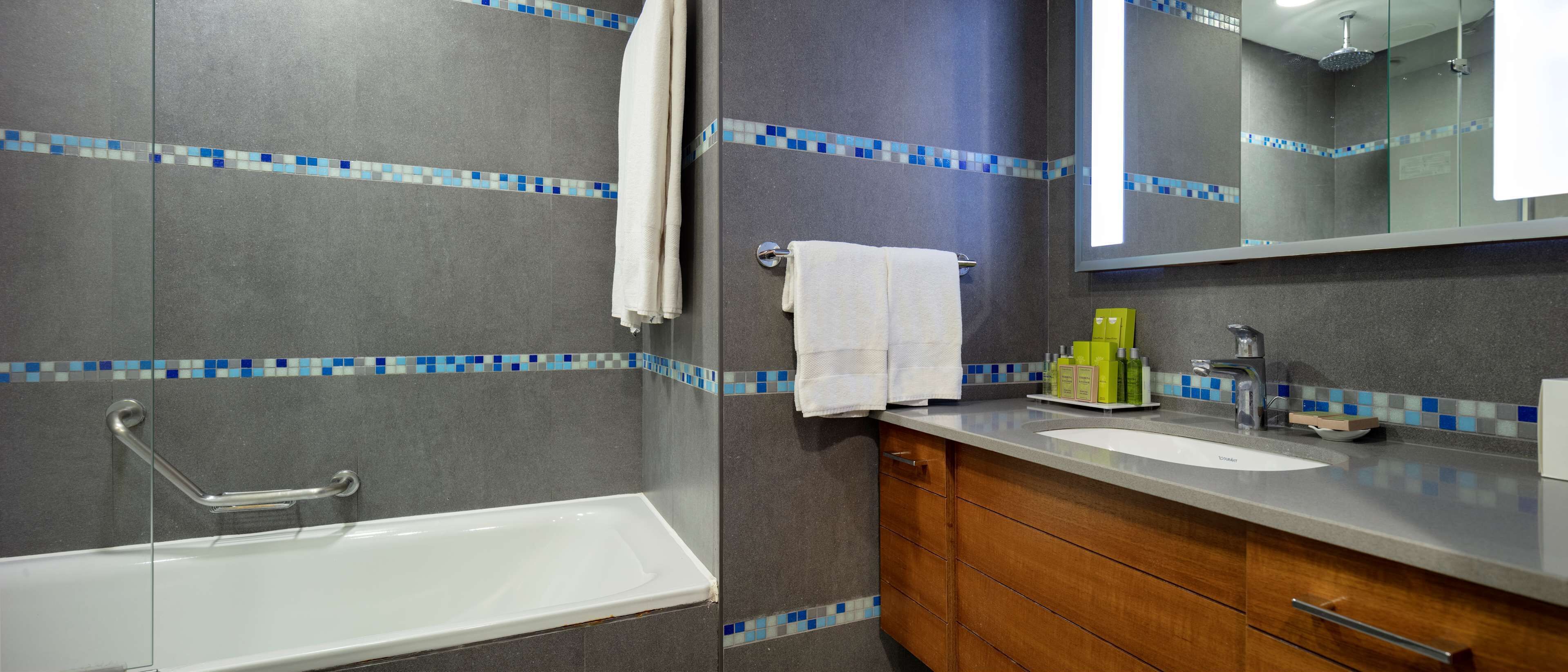 A bathroom with a bathtub, a sink, and a mirror.