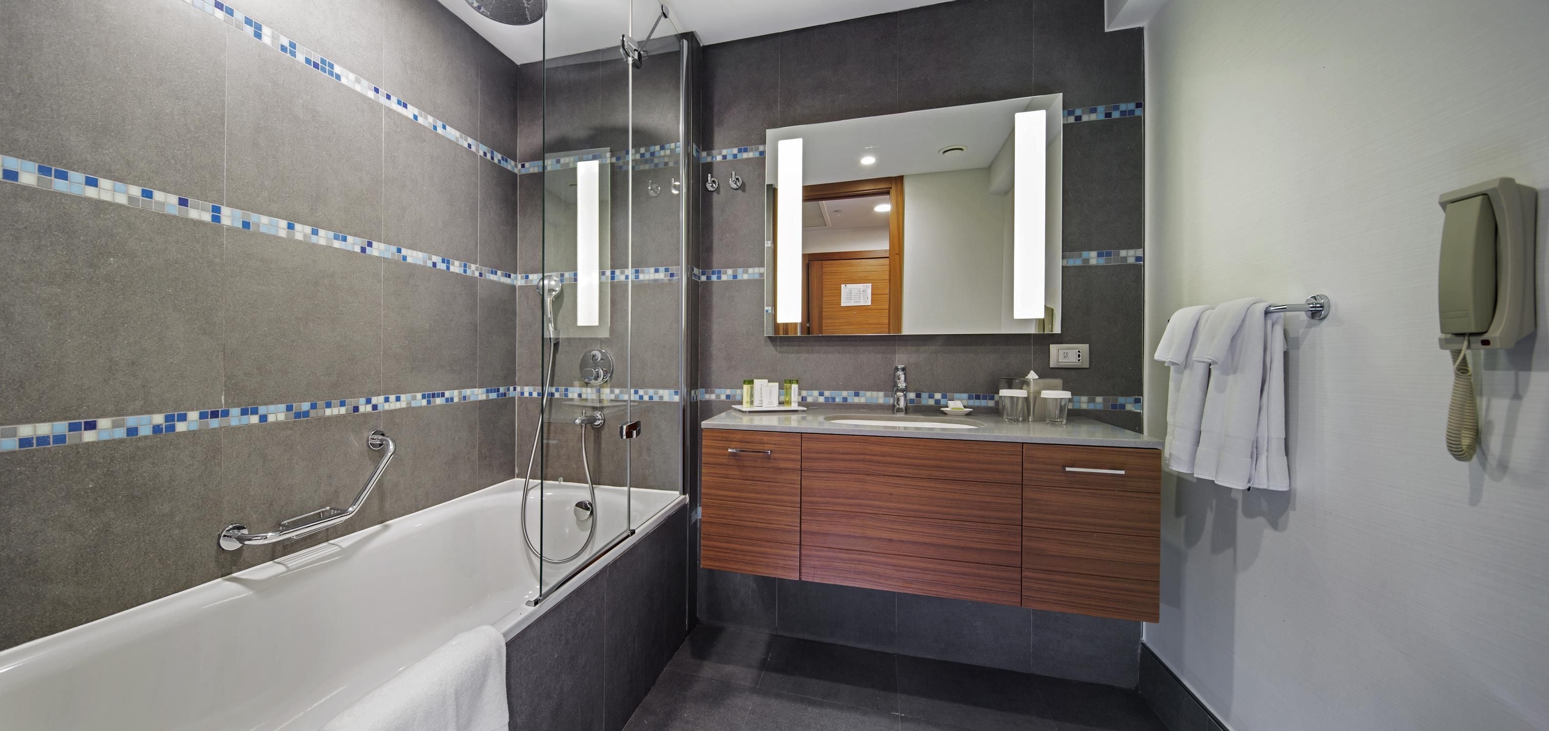 A modern bathroom with a bathtub, a glass-enclosed shower, and a vanity with a mirror.