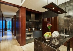 A modern kitchen with a marble countertop, a built-in oven, and a sink.