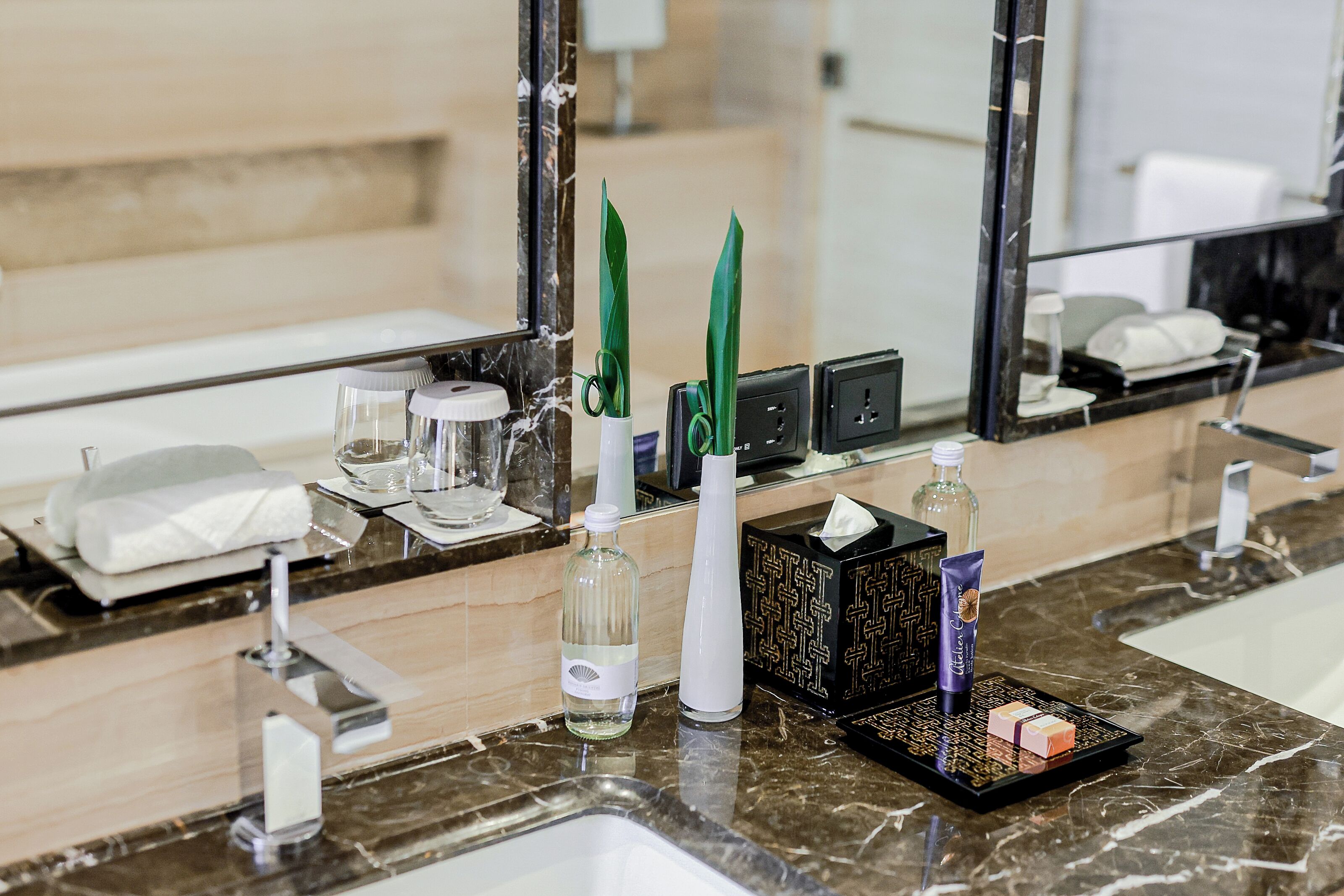 A bathroom vanity with a marble countertop, a mirror, a towel, a soap dish, and toiletries.