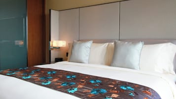 A hotel room with a bed, a nightstand, and a wall-mounted lamp.