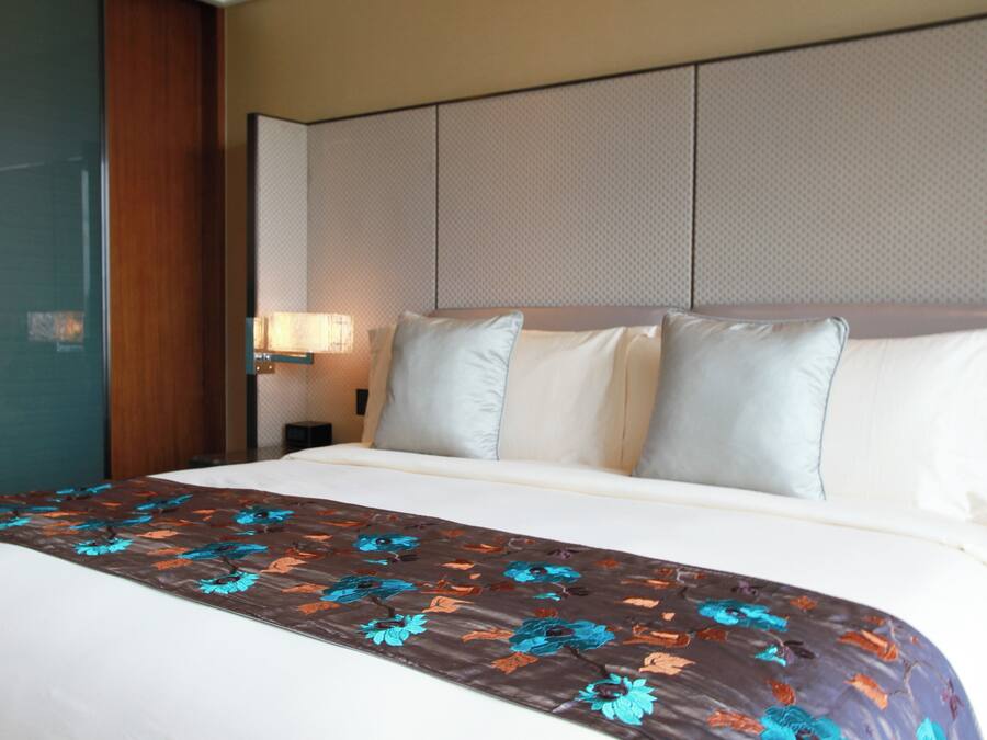 A hotel room with a bed, a nightstand, and a wall-mounted lamp.