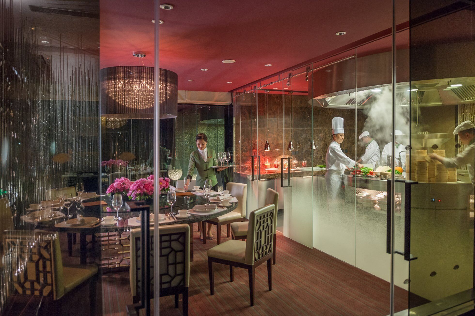 A restaurant with a glass partition separating the dining area from the kitchen.