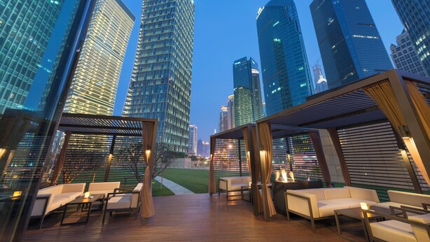 Terraza en la azotea con mobiliario moderno y vista al horizonte de la ciudad.