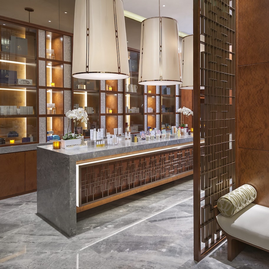 A modern hotel lobby with a marble floor, a reception desk with a counter, and large pendant lights.