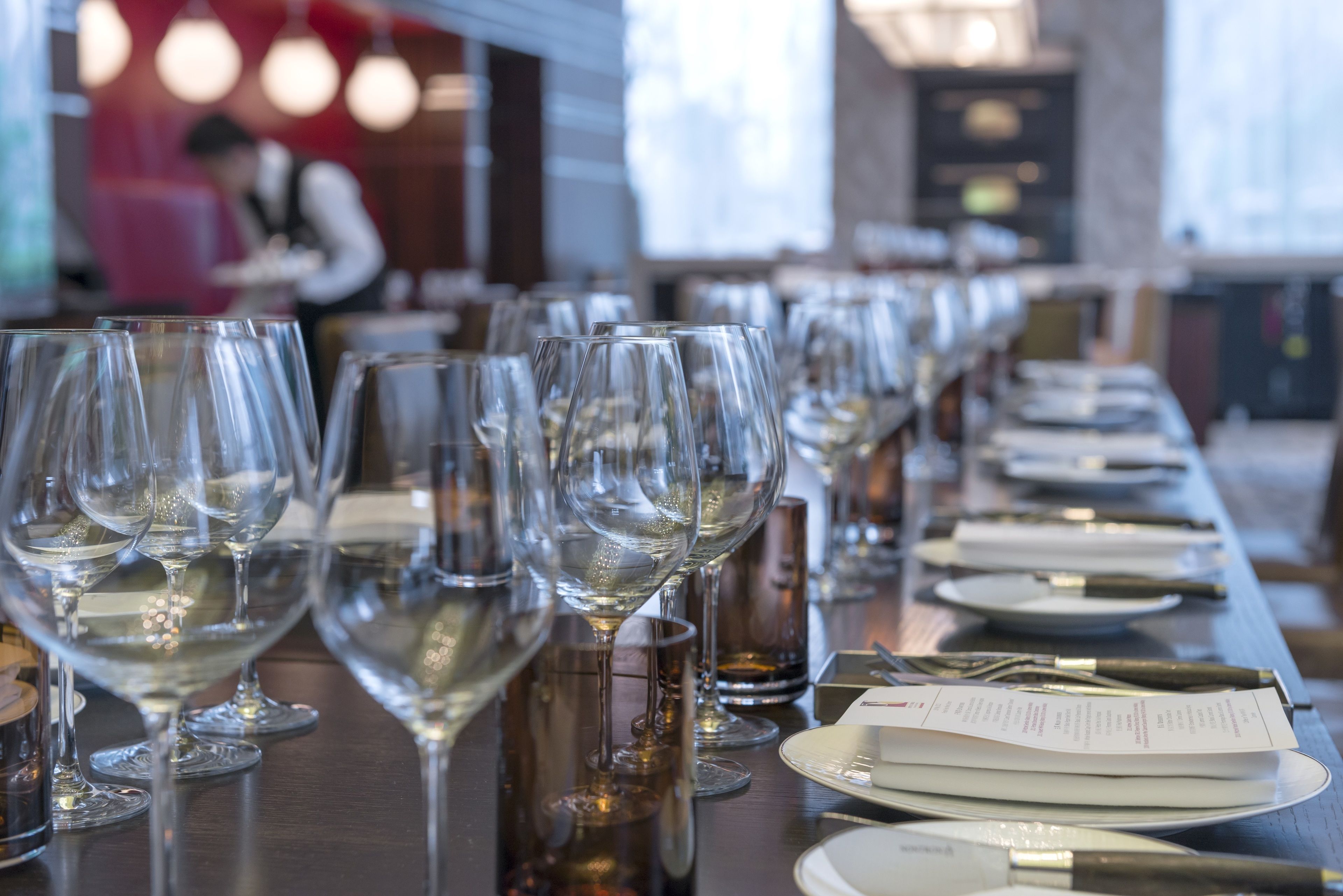 A long table set with multiple wine glasses, plates, and cutlery, likely in a dining area of a hotel or restaurant.