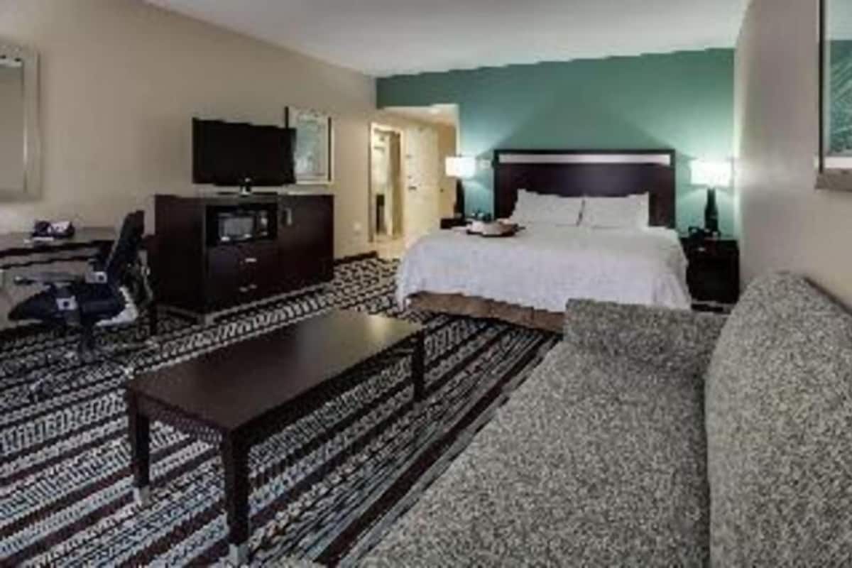 A hotel room with a bed, a television, a desk, and a sofa.