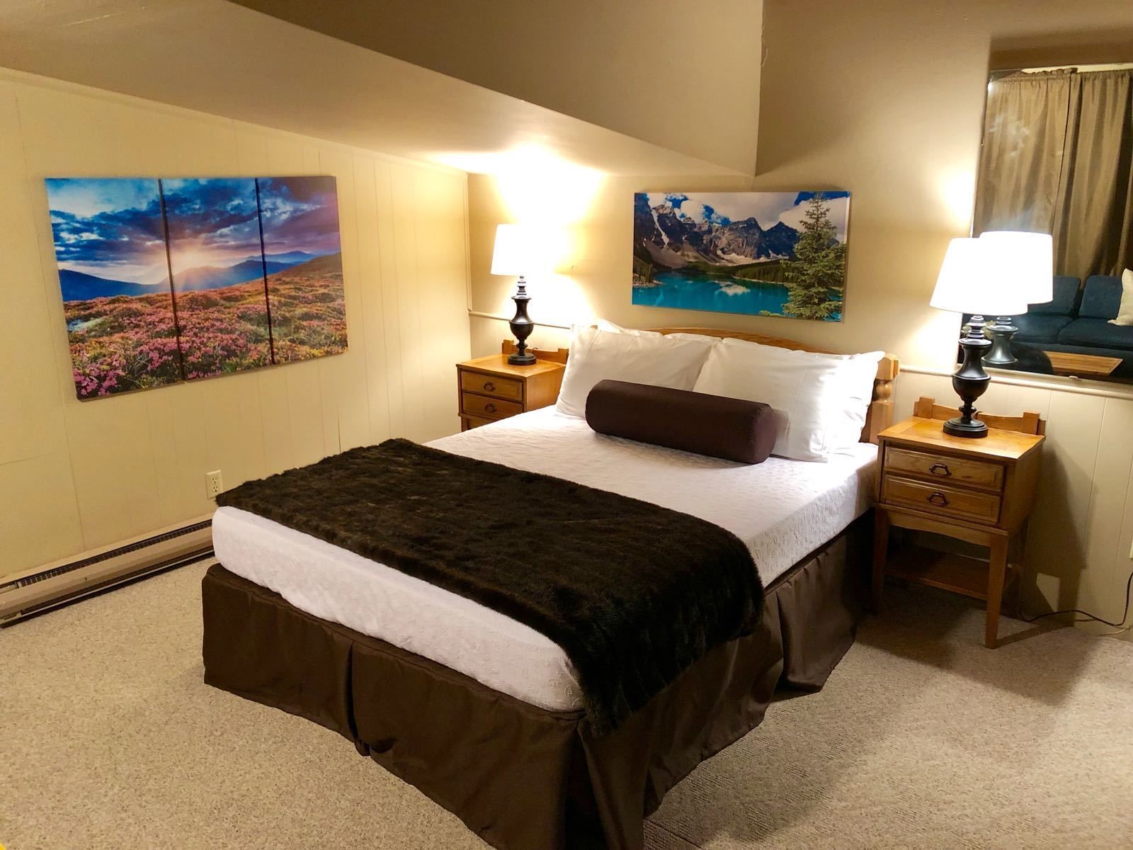 Una habitación de hotel con una cama grande, dos mesitas de noche y dos lámparas de pared.