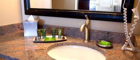A bathroom with a granite countertop, a white sink, a mirror, and a towel rack.